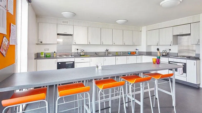 Kithcen showing long table with five stools and cooking area behind