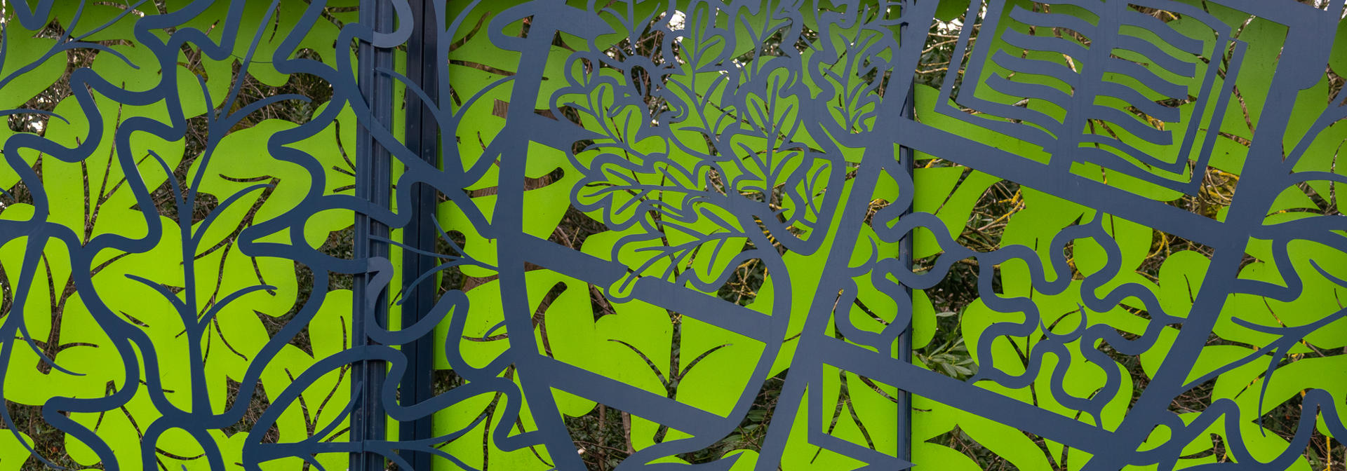 A decorative outdoor metal fence featuring a green background.