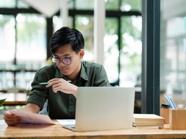 Student works on a laptop reviewing documents.