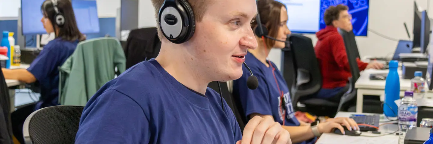 Staff working at a computer in an office with a headset.