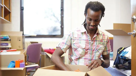 Student unpacking boxes in bedroom