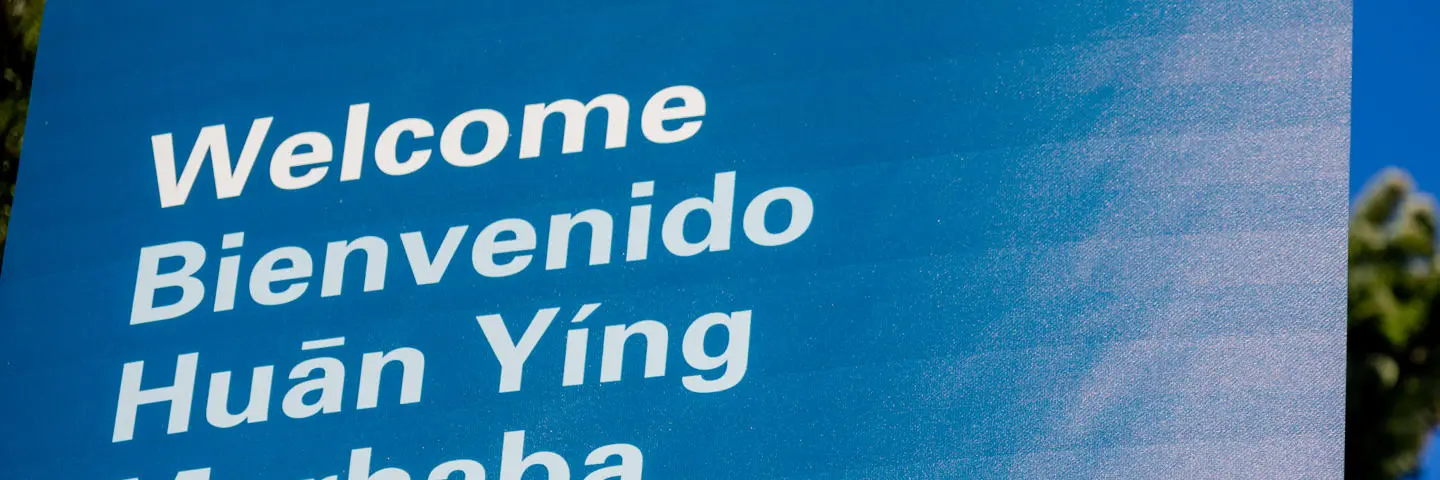 A blue sign with the word welcome written in different languages.